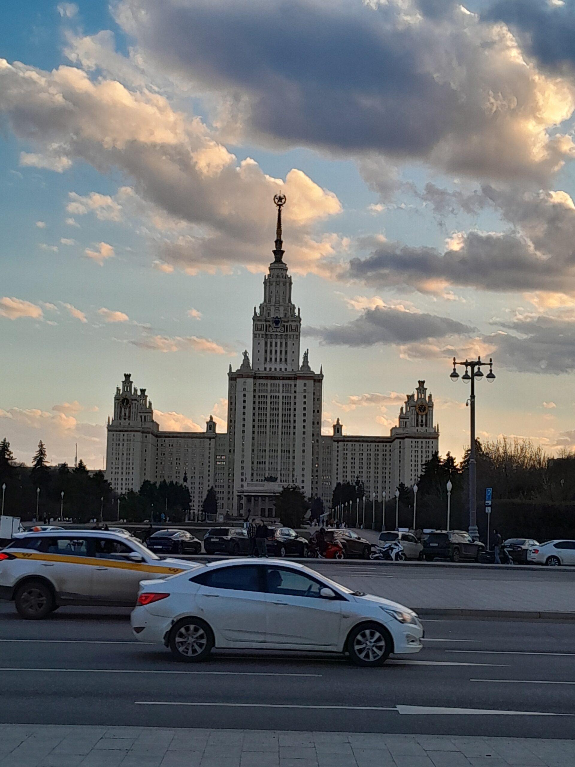 道路を走る車越しに見える、МГУ本館